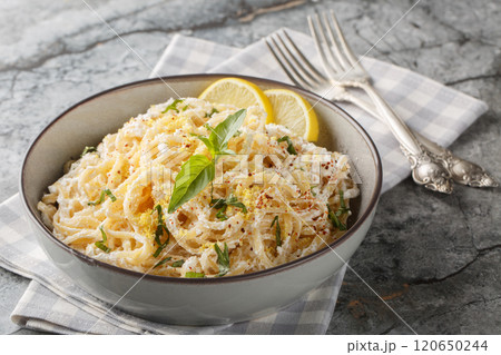 Italian spaghetti pasta with ricotta, lemon zest and juice, parmesan, pepper and basil close-up in a bowl. Horizontal 120650244