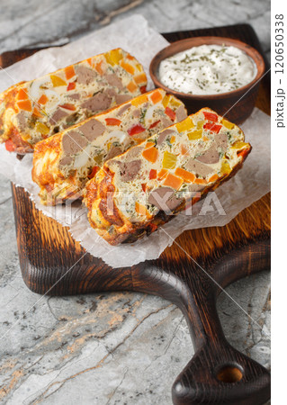 Chicken liver eggs vegetables casserole sliced close-up on wooden board on table. Vertical 120650338
