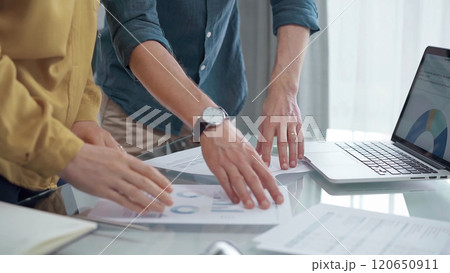 Business people, professionals analyzing financial charts and data on a desk while standing and using laptop computer in office Business people, professionals analyzing financial charts and data on a desk while standing and using laptop computer in office 120650911