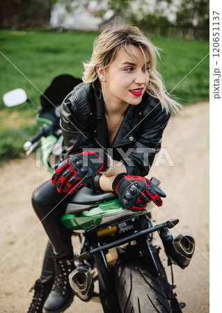Woman on Motorcycle in Leather Jacket. Stylish woman sits on a motorcycle, dressed in black leather Woman on Motorcycle in Leather Jacket. Stylish woman sits on a motorcycle, dressed in black leather 120651137