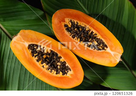 Juicy papaya fruit cut in half, with seeds and bright orange flesh top view. This photo highlights the freshness and nutritional value of papaya fruit, ideal for healthy food background. 120651326