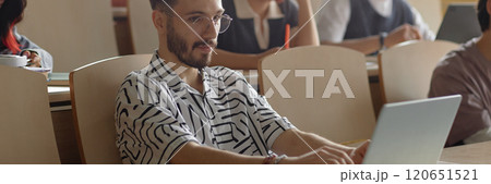Website header shot of young Middle Eastern male student with neat beard wearing glasses studying using laptop in lecture class at university, copy space Website header shot of young Middle Eastern male student with neat beard wearing glasses studying using laptop in lecture class at university, copy space 120651521