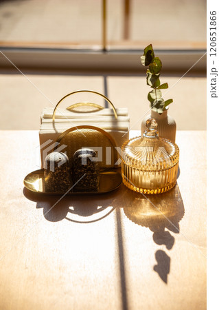 Cutlery, a napkin holder and a vase with a flower on a wooden table 120651866