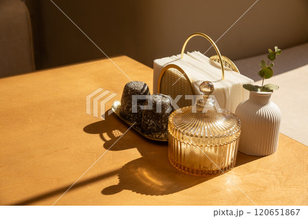Cutlery, a napkin holder and a vase with a flower on a wooden table 120651867
