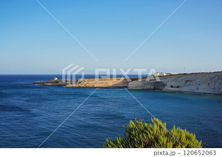 Expansive coastal cliff stretching into calm blue Mediterranean sea, serene landscape under clear sunny sky 120652063