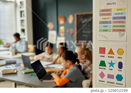 Background shot of educational posters on cupboard with colorful pictures of months of year and different geometric shapes in primary school classroom, copy space 120652299