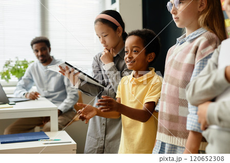 Side view of smiling young African American boy presenting homework results to class standing in line with classmates during lesson at school Side view of smiling young African American boy presenting homework results to class standing in line with classmates during lesson at school 120652308