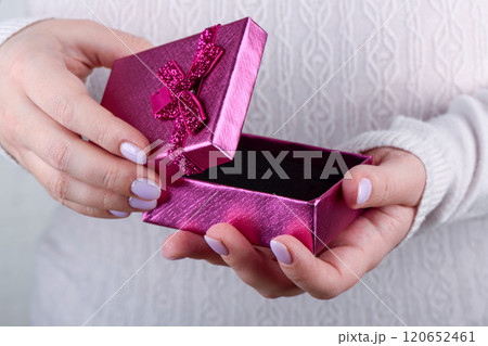 Open pink gift box in female hands with fashionable manicure. 120652461