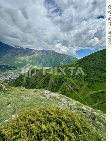 Panoramic view of the Caucasus mountain peaks, meadow and small town scape 120652685