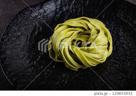 raw tagliatelle pasta, with spinach, homemade, top view, no people, on a black plate, cooking concept, 120653032