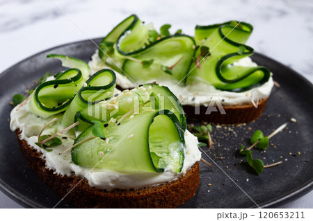 Breakfast, grain bread sandwiches, cream cheese, sliced cucumber, with microgreens, and sesame seeds, on a light table, close-up, top view, selective focus, no people, 120653211