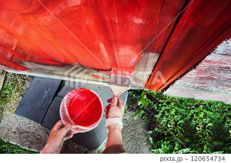 Painting entrance door red with wide flat brush, top view, close-up. 120654734