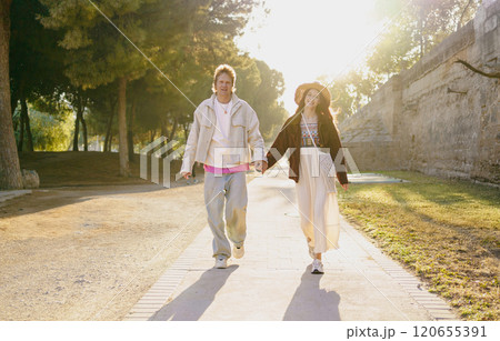 A young couple is happily walking hand in hand during the beautiful golden hour time 120655391