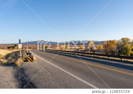 Open Road and Autumn Landscape in Grand Teton National Park Under a Clear Sky. 120655729
