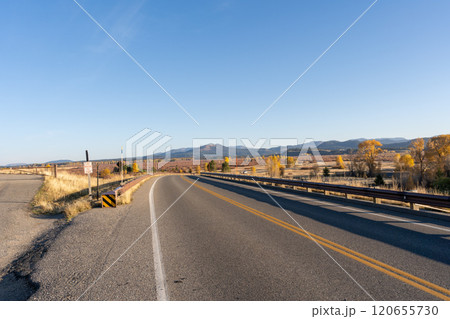 Open Road and Autumn Landscape in Grand Teton National Park Under a Clear Sky. 120655730