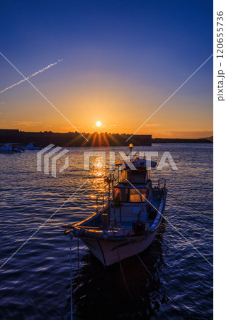 沈む夕日に照らされている一隻の漁船 沈む夕日に照らされている一隻の漁船 120655736