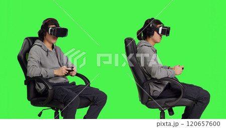 Asian person gaming with vr headset against greenscreen backdrop in studio, playing video games with controller. Young guy having fun with rpg competition, virtual reality leisure. 120657600
