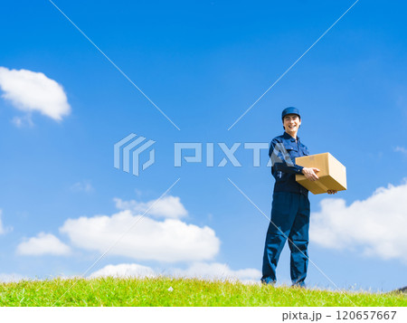 青空の下で荷物を持つ配達員・デリバリースタッフの男性 120657667
