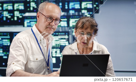 Senescent workers looking around innovative supercomputer hub, preparing to start comission on malfunctioning high tech infrastructure in order to ensure optimum operations 120657671
