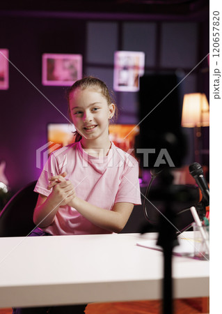 Excited child filming room tour inside home studio using mobile phone on tripod stabilizer. Gen Z influencer doing video presenting apartment to interested children subscribers Excited child filming room tour inside home studio using mobile phone on tripod stabilizer. Gen Z influencer doing video presenting apartment to interested children subscribers 120657820