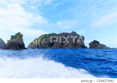 ヒリゾ浜渡船に乗って出港するスキンダイバー、シュノーケラー。 青い海と無人島の大根島、岩礁が見える。 120657842