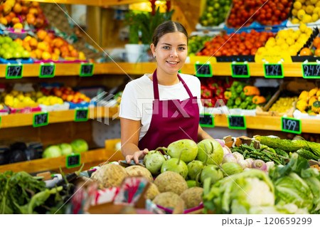 Young saleswoman working and posing in store near counter with round bottlegourd vegetable 120659299