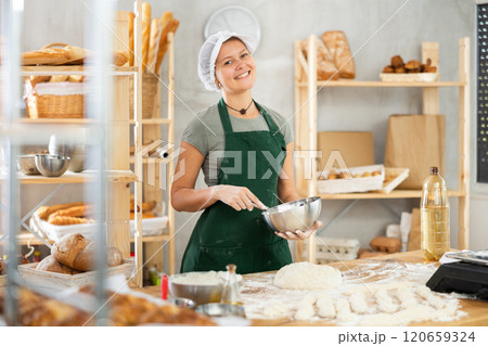 Female bkery cook whisks chicken eggs to make dough in bakery kitchen Female bkery cook whisks chicken eggs to make dough in bakery kitchen 120659324