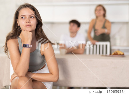 Mother-in-law and son scold young daughter-in-law in home kitchen 120659384