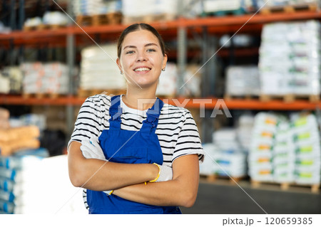Positive warehouse girl employee stands with arms crossed over chest. 120659385