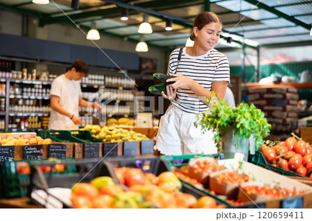 Young woman choosing zucchini in grocery store 120659411