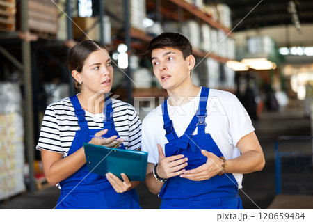 Young woman and young guy warehouse workers checking documents Young woman and young guy warehouse workers checking documents 120659484