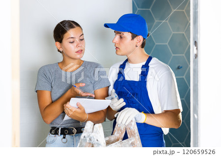Young worker discusses project documentation of bathroom desing with a girl client 120659526
