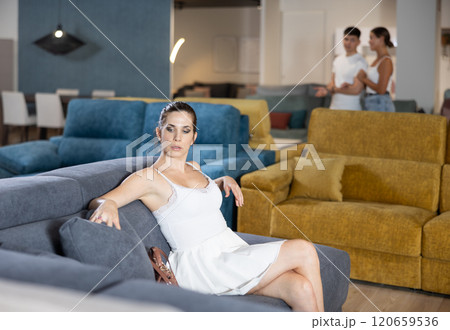 Adult happy smiling female touching sofa in the furniture store before buying 120659536