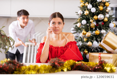 Annoyed young male and female getting mad at each other while standing near of Christmas tree in apartment Annoyed young male and female getting mad at each other while standing near of Christmas tree in apartment 120659631