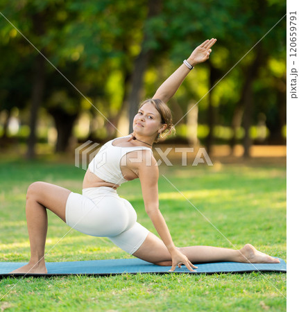 Young yogini performing Crescent Low Lunge Pose in summer park Young yogini performing Crescent Low Lunge Pose in summer park 120659791