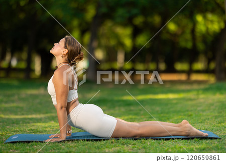 Girl doing Upward Facing Dog yoga pose in summer park 120659861