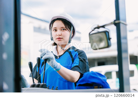 フォークリフトを操縦するヘルメット姿の女性 120660014