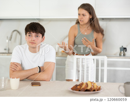 Young woman quarrels with young guy in kitchen Young woman quarrels with young guy in kitchen 120660059