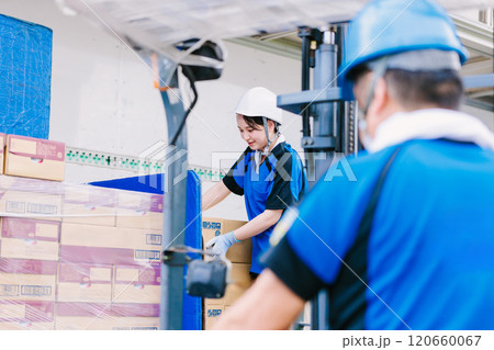 トラックにフォークリフトで荷物を積むヘルメット姿の作業員 120660067