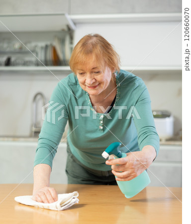 Happy mature woman cleaning her kitchen with radiant smile Happy mature woman cleaning her kitchen with radiant smile 120660070