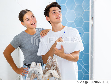 Young couple with documents checks the number of tiles, making important notes Young couple with documents checks the number of tiles, making important notes 120660104