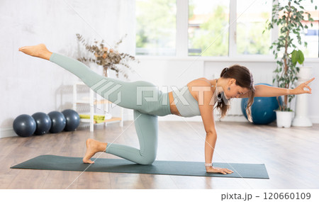 Young woman yoga trainer performing table pose on black rug Young woman yoga trainer performing table pose on black rug 120660109