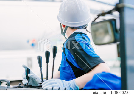 フォークリフトを操縦するヘルメット姿の女性 フォークリフトを操縦するヘルメット姿の女性 120660282