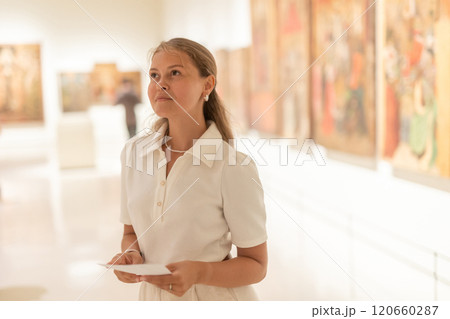 Portrait of young attractive woman holding an information booklet during a visit to fine arts museum 120660287