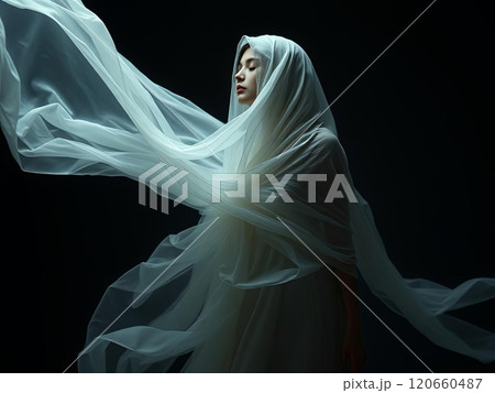 A woman dressed in a beautiful white gown is elegantly wrapped in a delicate white cloth, creating a striking visual appeal 120660487
