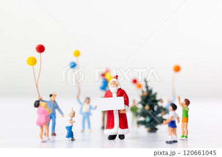 Miniature Santa Claus holding a gift surrounded by children and colorful balloons Miniature Santa Claus holding a gift surrounded by children and colorful balloons 120661045