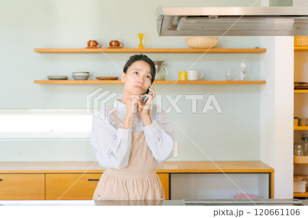 キッチンで電話をする女性 120661106
