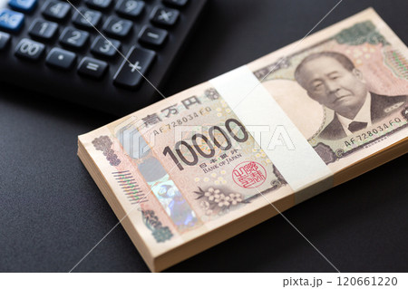 黒い背景に置かれた新一万円札の札束と黒い電卓 120661220