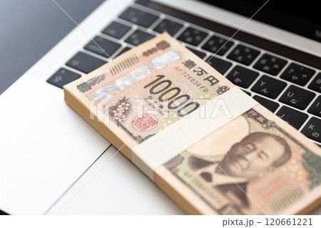 黒い背景に置かれた新一万円札の札束とパソコン 黒い背景に置かれた新一万円札の札束とパソコン 120661221
