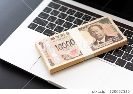 黒い背景に置かれた新一万円札の札束とパソコン 黒い背景に置かれた新一万円札の札束とパソコン 120662529